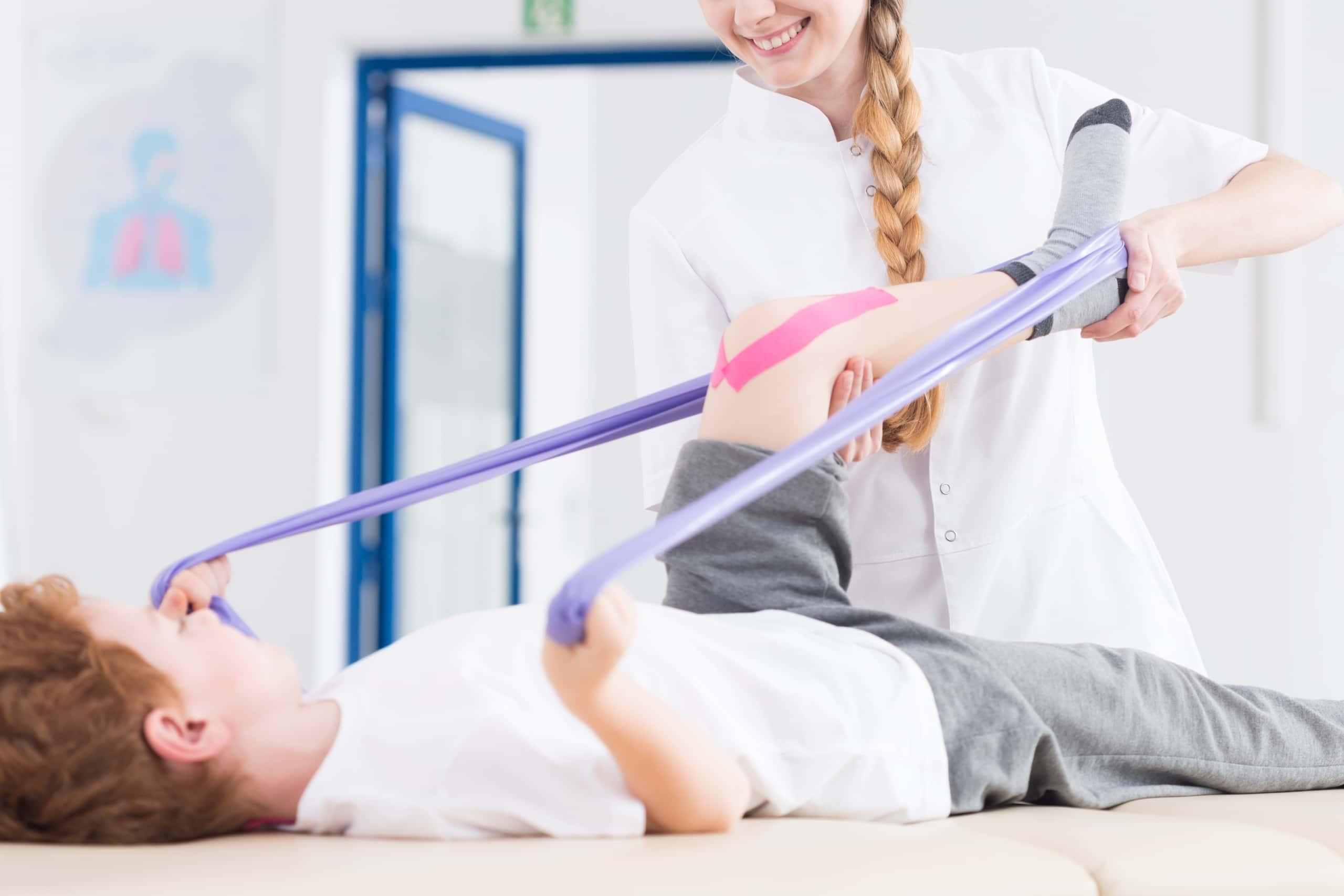 Physical Therapist Assistant helping a pediatric patient use exercise bands